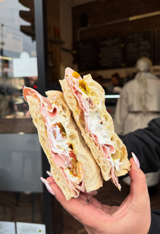 The Bologna schiacciata, cut in two and held in front of the chalkboard